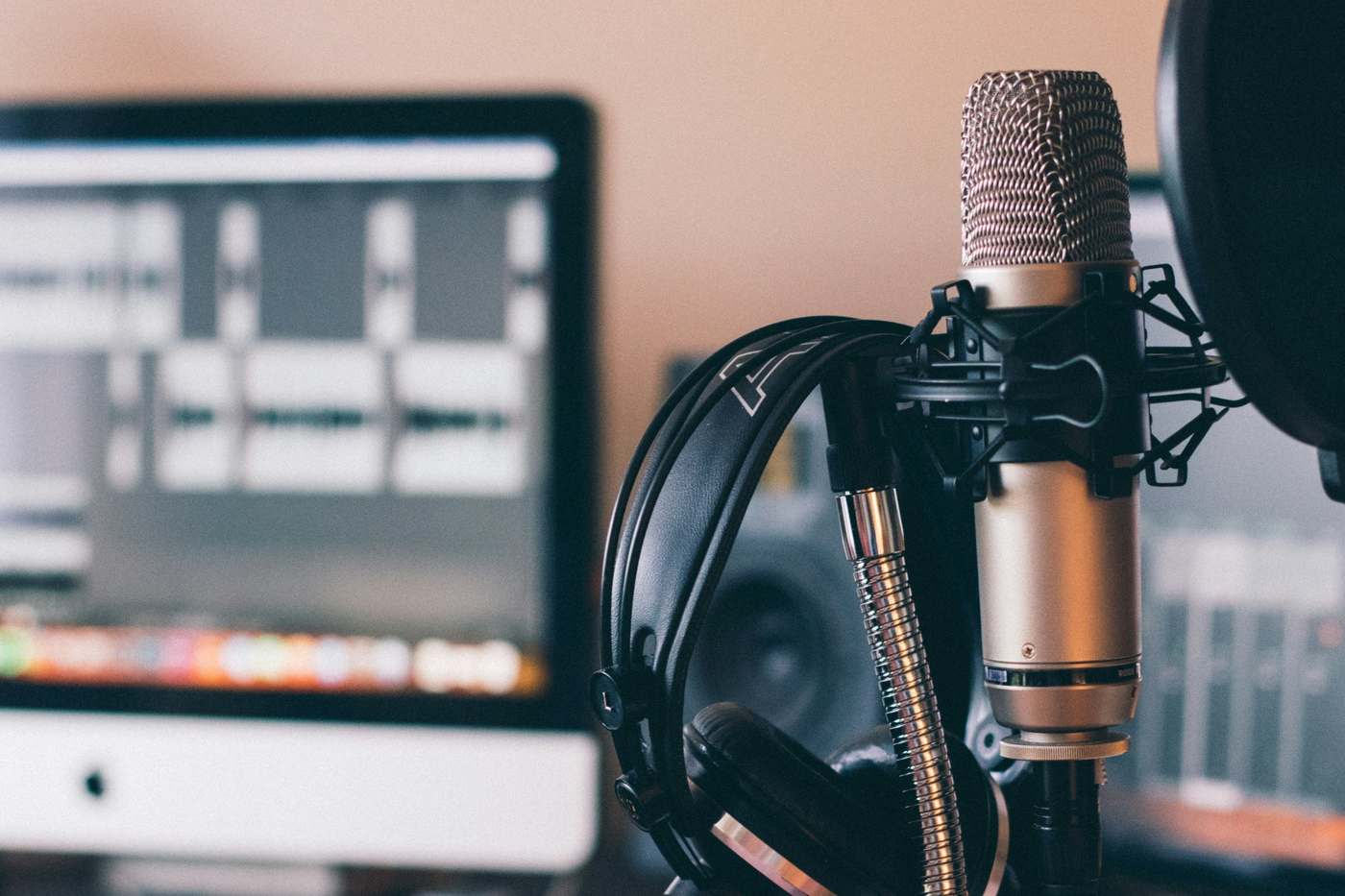 Condenser microphone with headphones and a monitor on a desk